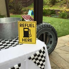 a yellow and black sign sitting on top of a table next to a potted plant