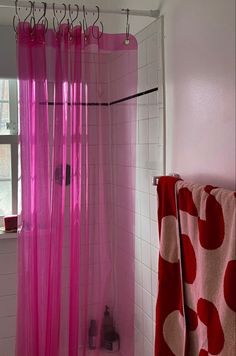 a pink shower curtain in a bathroom next to a window