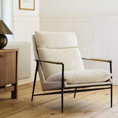 a chair sitting on top of a hard wood floor next to a table with a lamp