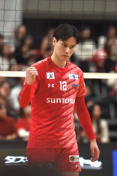 a young man holding a volleyball ball in front of a net