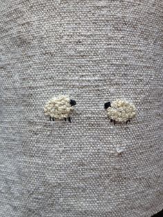 two sheep are shown on the side of a piece of fabric with eyes drawn in it