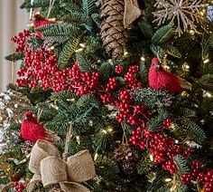 a christmas tree decorated with red berries, pine cones and burlocked bows