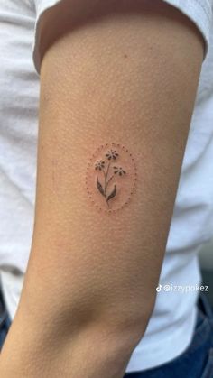 a woman's arm with a small flower tattoo on the back of her left arm