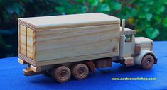 a toy truck with a wooden box on the back is sitting on a blue surface