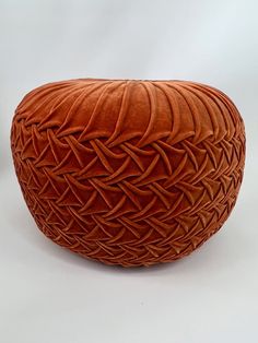 an orange woven basket sitting on top of a white table