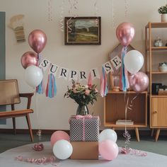 balloons and streamers are hanging from the ceiling above a table with presents on it