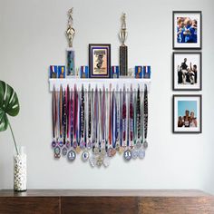 a bunch of medals are hanging on the wall above a wooden cabinet with pictures and vases