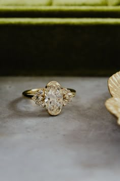 a gold ring sitting on top of a table next to a leaf shaped flower vase