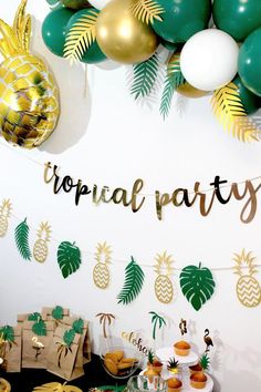 a tropical themed party with pineapples, palm trees and gold foiled balloons