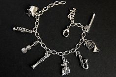 A collection of silver plated musical instrument charms have been dispersed around a shimmering silver plated bracelet chain in this handmade charm bracelet. This orchestra charm bracelet is then completed with a lobster clasp and a 1/2 inch of chain at the end for adjustable sizing. Charms in this bracelet include a piano charm, trumpet charm, violin charm, clarinet charm, cellist charm, saxophone charm, French horn charm, flute charm, and xylophone charm. ● Sizing ● To determine your bracelet Lover Bracelet, Music Bracelet, Handmade Charm Bracelets, Lovers Bracelet, Easter Sale, Silver Plated Bracelet, Music Lover, Musical Instrument, Bracelet Handmade