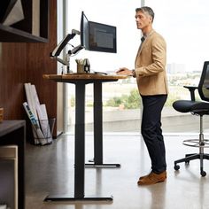 a man standing in front of a desk with a computer on it