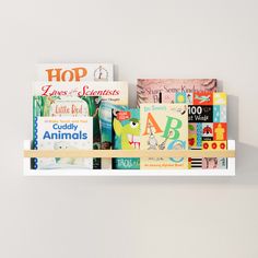 The kids book shelf used as a book display, showcasing a variety of colorful children's books. The white shelf and natural wooden rod contrast beautifully with the vibrant book covers. Cute Reading Corner, Shelves For Nursery, Floating Shelves White, Organizing Kids Books, Kids Book Shelf, Modern Bookshelf Design, Book Shelf Wall, Organize Kids, Kids Bedroom Organization