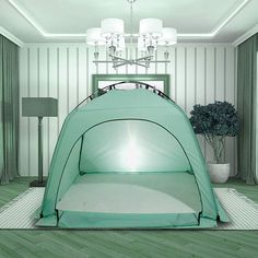 a green tent sitting on top of a hard wood floor next to a potted plant