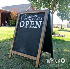 an open sign sitting in the grass outside