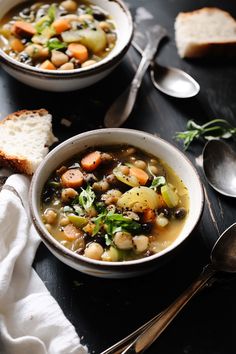 two bowls filled with soup next to bread and spoons