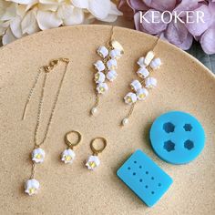 some jewelry is laying on a plate next to a flower and a blue plastic object