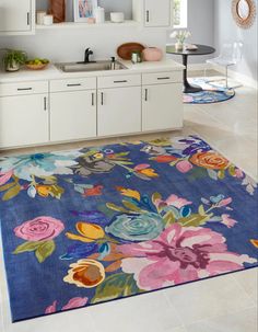 a blue rug with flowers on it in a kitchen area next to a sink and cabinets