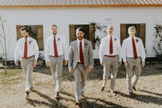 a group of men wearing ties walking next to each other in front of a white building