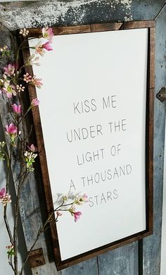 a sign that says kiss me under the light of a thousand stars hanging on a door