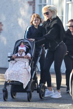 two women pushing a stroller with a baby in it and another woman walking behind them