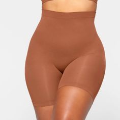 This Mid Waist Short Hits At The Mid Thigh And Is The Perfect Solution For Strong Tummy And Waist Control With Extra Compression Along The Back Thighs For A Lifted Look. Features Large Round Butt Pockets For A Defined Butt, An Interior Silicone Underband To Prevent Rolling, And An Open Gusset. Fits True To Size. Underband With Interior Silicone To Prevent Rolling, Strong Compression Along Tummy, Waist And Thighs, Pockets At Butt To Lift And Add Definition, Strong Compression Along Back Thigh To Help Provide Lift, Hits At Mid Thigh, Open Gusset Amber Is Size 12, 36dd, And 5’ 11", Wearing Skims L 78% Nylon / 22% Spandex Machine Wash Cold, Do Not Bleach, Tumble Dry Low Imported These A Seamless Mid-thigh Shapewear, Solid Seamless Short Shapewear, Solid Short Seamless Shapewear, Solid Color Shaping High-cut Leg Shorts, Solid Color Seamless Mid-thigh Bottoms, Seamless Brown Shapewear, Solid Color Mid-thigh Length Shapewear, Compressive Shapewear Bottoms For Loungewear, Compressive Loungewear Shapewear Bottoms