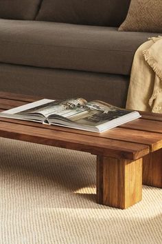 a wooden coffee table sitting on top of a carpeted floor next to a couch