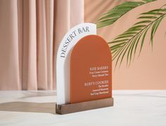 an orange and white plaque sitting on top of a table next to a potted plant