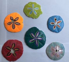 four different colored stones with designs on them sitting next to each other in the shape of flowers