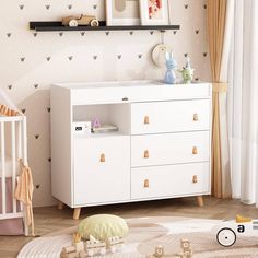 a baby's room with white furniture and wallpaper