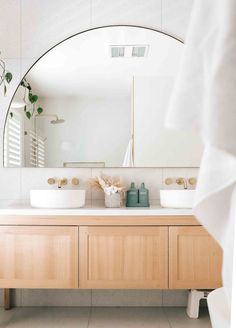 a bathroom with two sinks and a large round mirror above the sink is seen in this image