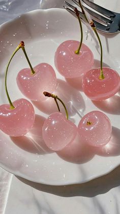 four cherries on a plate with a fork