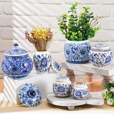 several blue and white vases sitting on top of a wooden table next to flowers