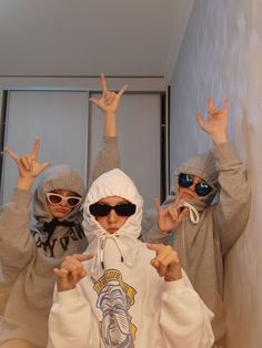 three young children wearing hoodies and sunglasses posing for the camera with their hands in the air