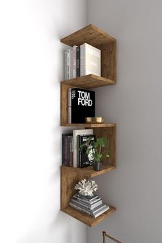 three wooden shelves with books and magazines on them in a corner next to a white wall