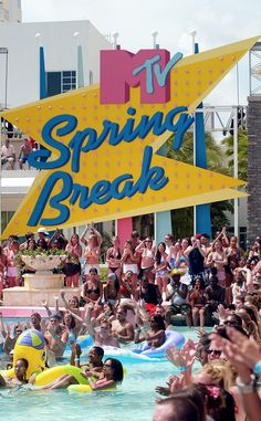 a group of people standing in front of a large sign that says spring break on it