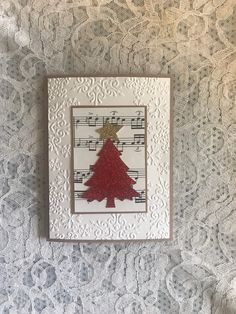 a red christmas tree with music notes on it is framed in a white lace background