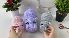 three crocheted stuffed animals sitting on top of a table next to potted plants