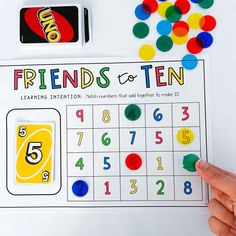 someone is holding up a game to play with their friends and tens on the table