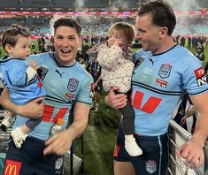 two men and a baby are standing in the stands at a sporting event