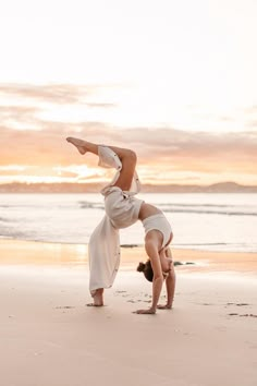 a woman doing a handstand on the beach