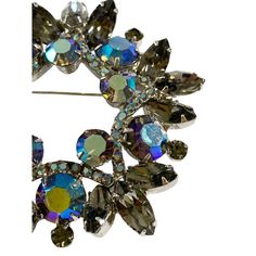 Luxuriously crafted , this 2.75" diameter, 0.5" h Vintage  Rhinestone Crystal Wreath Brooch displays the vibrant Aurora Borealis for a classic, elegant look.  The setting is solid silver-tone and has a secure functioning pin. Perfectly preserved in its condition, this circular faceted pin will bring a unique touch to any outfit. AB bead treatments were invented by Swarovski back in 1956, in partnership with Christian Dior. Elegant Diamond Multi-stone Brooch, Brooch Display, Vintage Green Rhinestone Brooches, Vintage Multicolor Rhinestones Brooches, Vintage Multicolor Multi-stone Brooch, Vintage Gold Multi-stone Brooches, Aurora Borealis, Vintage Rhinestone, Crystal Rhinestone