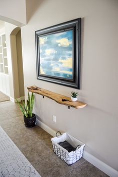 a painting hanging on the wall next to a potted plant in a black and white basket