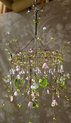 a chandelier hanging from the ceiling with green and pink flowers on it's branches