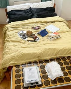 an unmade bed with books and other items on it