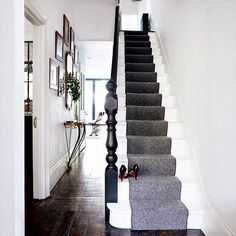 the stairs are lined with gray carpet and white walls, along with pictures on the wall