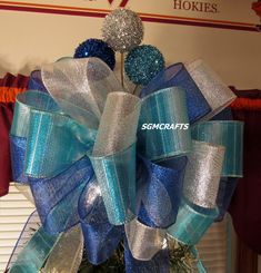 a blue and silver bow on top of a christmas tree