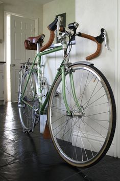 a green bicycle parked next to a white wall