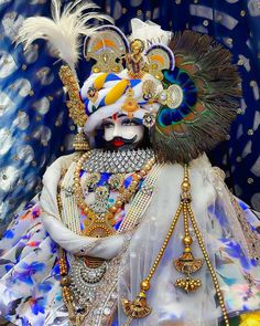 an elaborately decorated costume with feathers and jewels on it's head, in front of