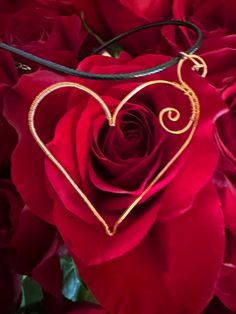 a close up of a red rose with a gold heart on it's necklace