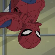 a spider - man hanging upside down in front of a glass window with his eyes open